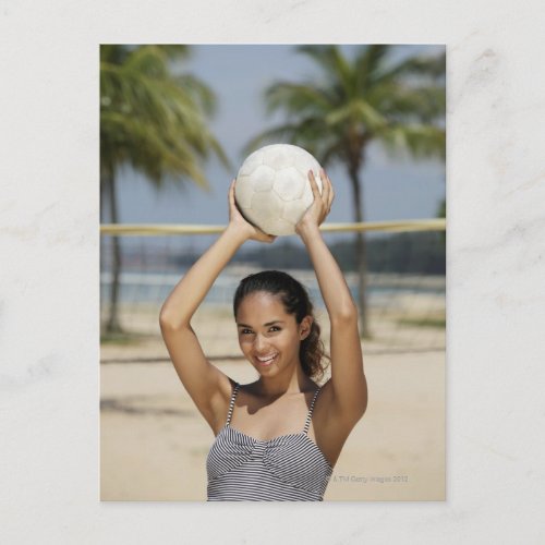 Young woman holding volleyball and smiling at postcard