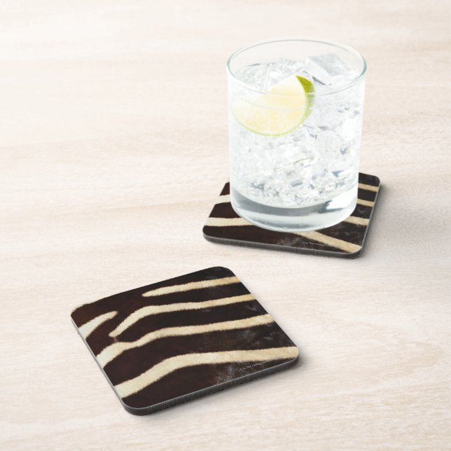 Black and white striped stone coasters are shown in use with a glass. 